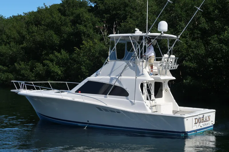 Slide: The Image of 2002 Luhrs 40 Convertible yacht on calm water, surrounded by lush greenery. - 7