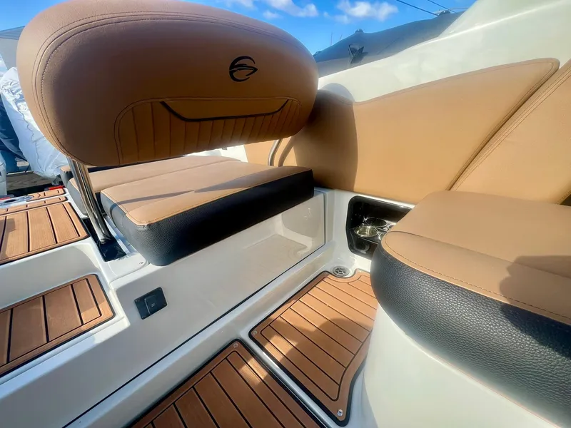Slide: The Image of 2025 Crownline 310 XSS boat interior with tan and black seating, wood accents. - 18
