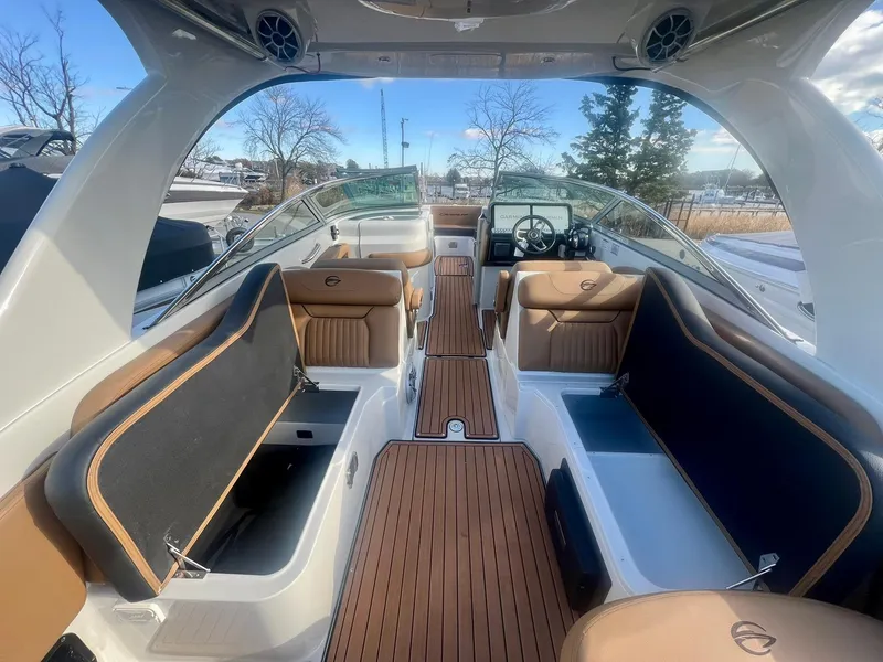 Slide: The Image of 2025 Crownline 310 XSS boat interior with luxurious seating and wood flooring. - 19