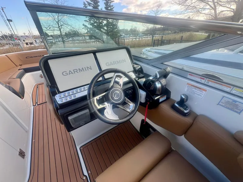 Slide: The Image of 2025 Crownline 310 XSS boat cockpit with Garmin displays and brown leather seating. - 24