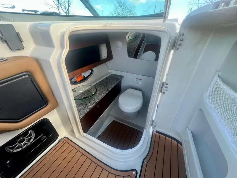 Slide: The Image of 2025 Crownline 310 XSS boat interior with modern bathroom and wooden flooring. - 26
