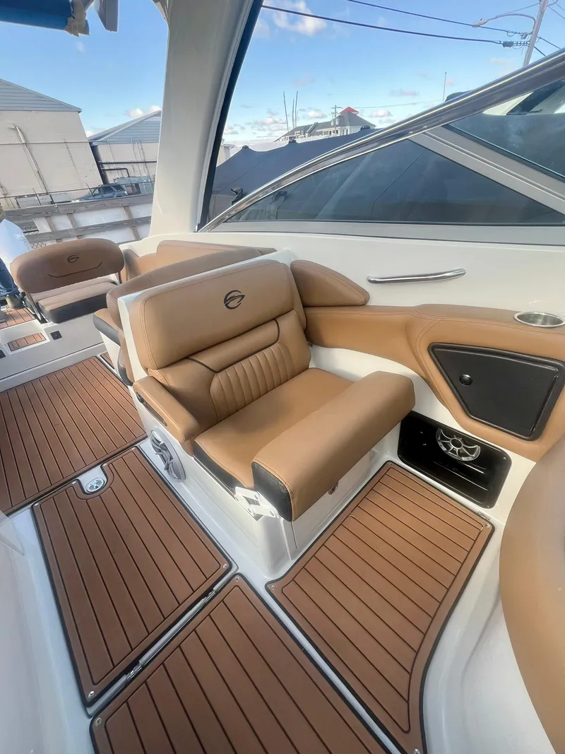 Slide: The Image of 2025 Crownline 310 XSS boat interior with tan leather seating and wood-style flooring. - 28