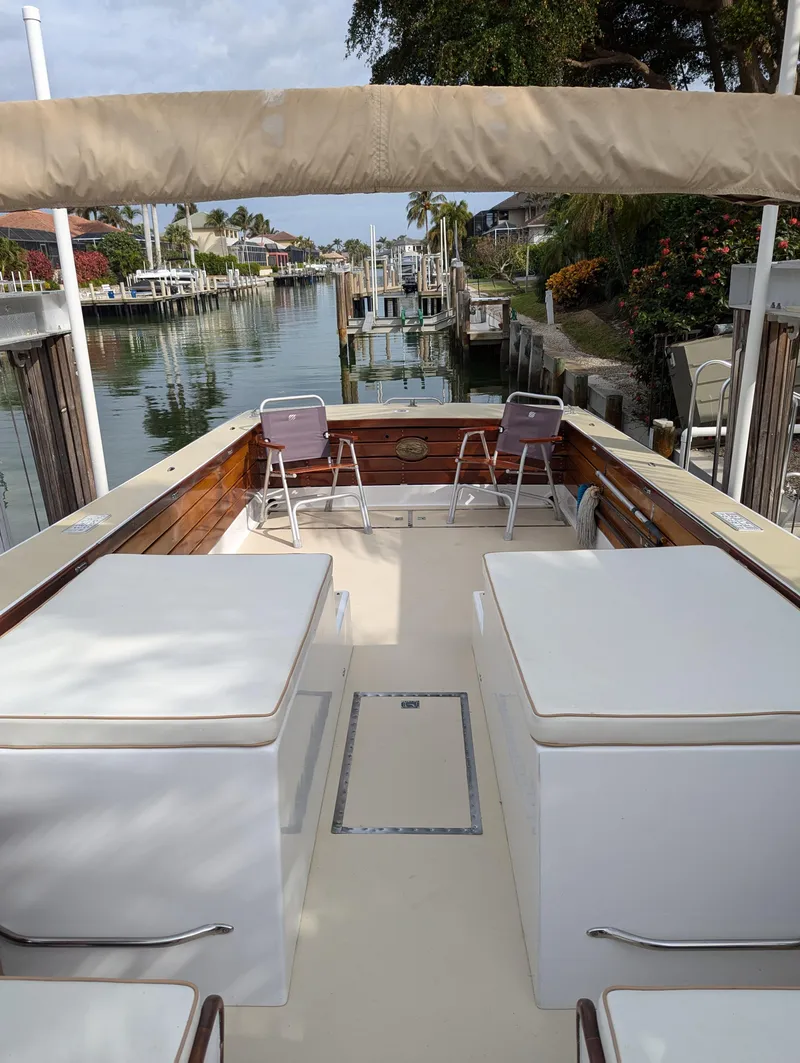 Slide: The Image of 1951 Huckins Fairform Flyer boat with spacious deck and seating, docked in a scenic canal. - 18
