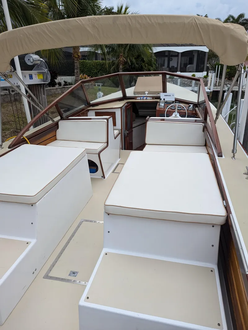 Slide: The Image of 1951 Huckins Fairform Flyer boat with beige seating and canopy, docked near palm trees. - 20
