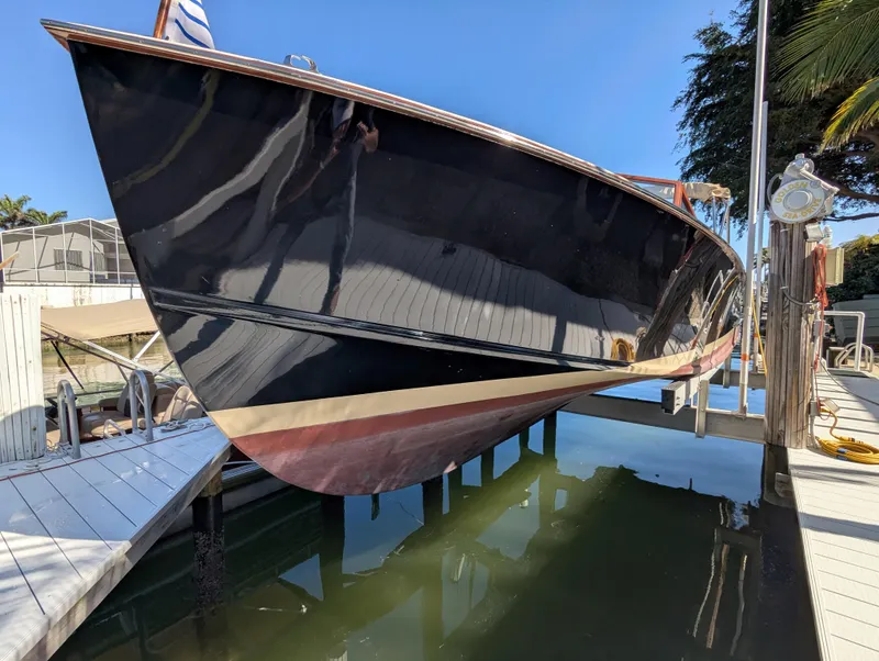 Slide: The Image of 1951 Huckins Fairform Flyer boat docked, reflecting on calm water under clear blue sky. - 5