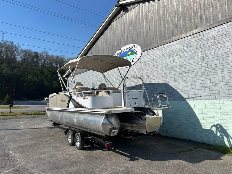 Slide: The Image of 2025 Avalon 2385 LSZ Rear Lounger pontoon boat on trailer, parked outside a building. - 4