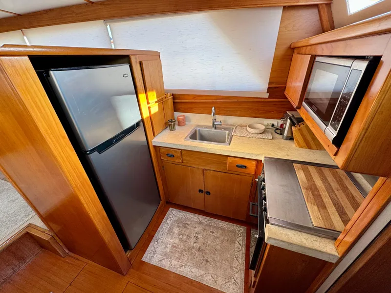 Slide: The Image of 1972 Stephens Brothers Flush Deck Motoryacht kitchen with wood cabinetry, sink, fridge, and microwave. - 15