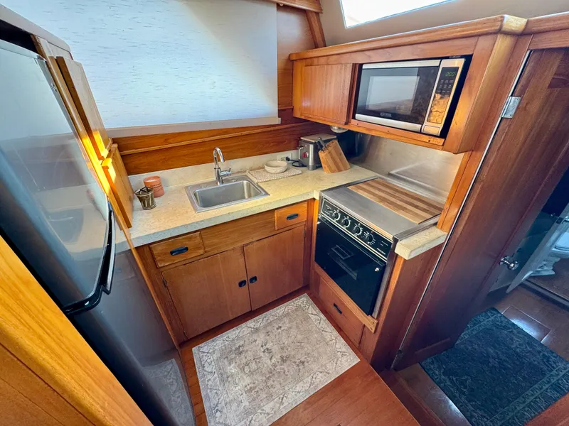 Slide: The Image of 1972 Stephens Brothers Flush Deck Motoryacht kitchen with wood cabinetry, sink, stove, and microwave. - 16