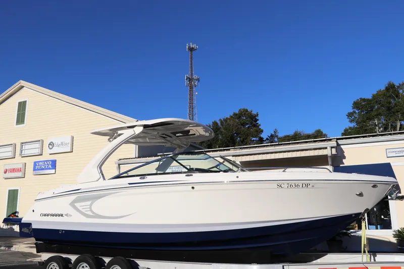The Image of 2021 Chaparral 30 Surf boat on trailer, parked outside a building under clear blue sky. - 0
