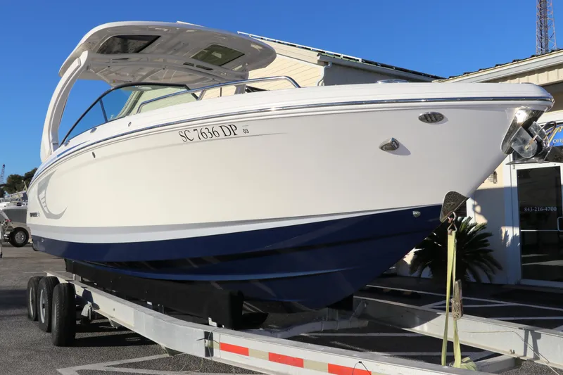 Slide: The Image of 2021 Chaparral 30 Surf boat on trailer, white and blue design. - 1