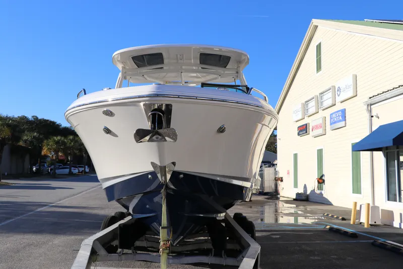 Slide: The Image of Chaparral 30 Surf 2021 boat on trailer, parked near a building under clear blue sky. - 2