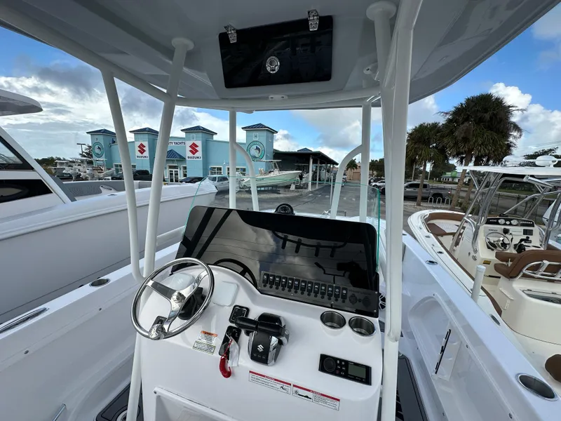 Slide: The Image of 2025 Twin Vee 240 GFX CC boat console with steering wheel and controls, docked at marina. - 4