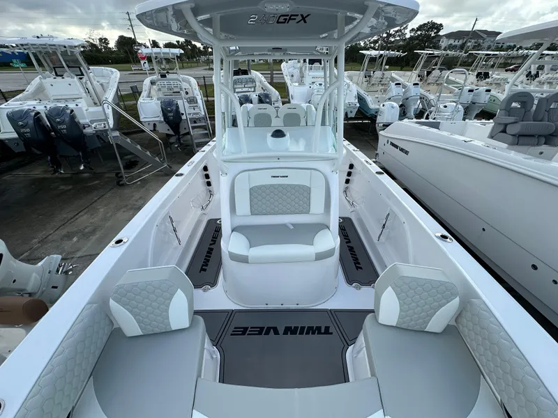 Slide: The Image of 2025 Twin Vee 240 GFX CC boat interior with seating and console, docked among other boats. - 6