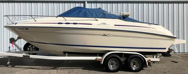 Slide: The Image of 1996 Sea Ray 215 Express Cruiser on trailer, covered, parked by metal wall. - 16