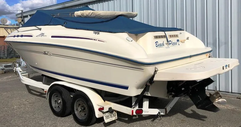 Slide: The Image of 1996 Sea Ray 215 Express Cruiser on trailer, blue cover, parked by metal building. - 17