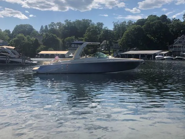 Slide: The Image of 2022 Chris-Craft Launch 28 GT boat on a serene lake with trees and houses in the background. - 1