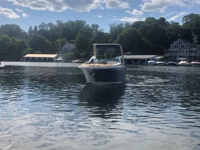 Slide: The Image of 2022 Chris-Craft Launch 28 GT boat on a serene lake with scenic background. - 2