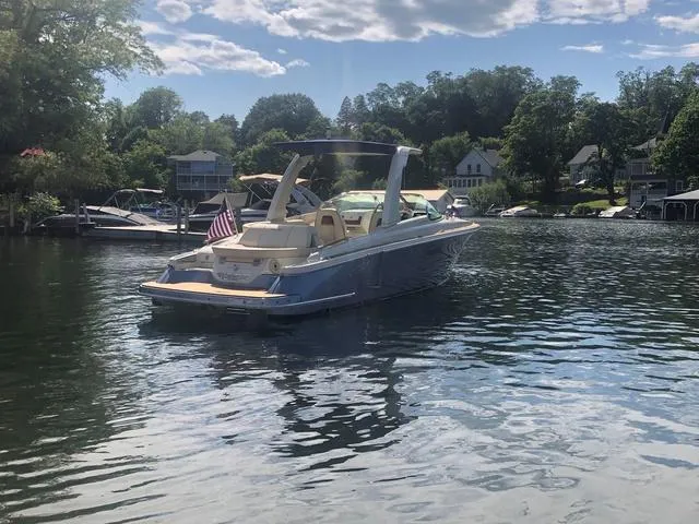 Slide: The Image of 2022 Chris-Craft Launch 28 GT boat on a serene lake with trees and houses. - 5