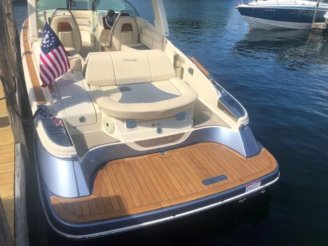 Slide: The Image of 2022 Chris-Craft Launch 28 GT boat with American flag, docked on calm water. - 7
