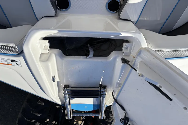Slide: The Image of Open storage compartment on a 2021 Yamaha Boats 212XE, featuring a foldable ladder. - 15