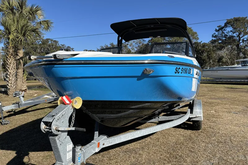 Slide: The Image of 2021 Yamaha Boats 212XE in blue on trailer, parked outdoors under clear sky. - 6