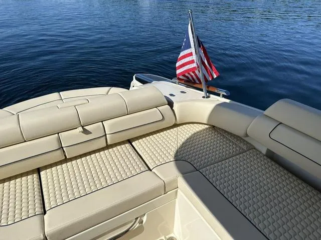 Slide: The Image of 2021 Chris-Craft Launch 31 GT boat with beige seating and American flag on calm water. - 24