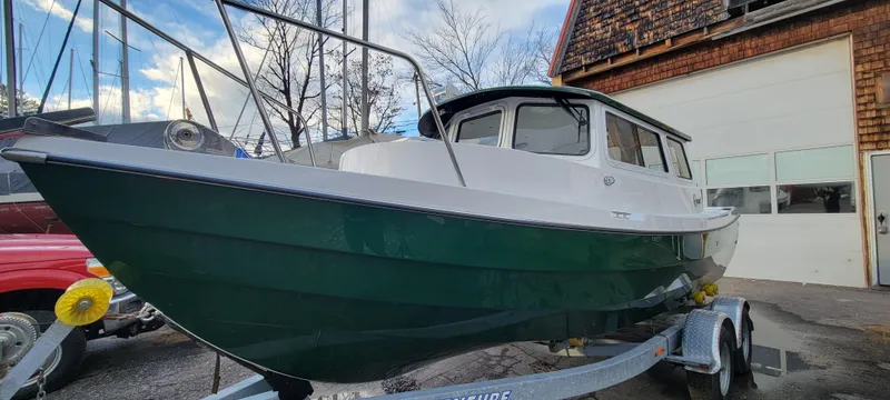 Slide: The Image of 2025 C-Dory 22' Cruiser on trailer, parked outdoors near a building. - 2
