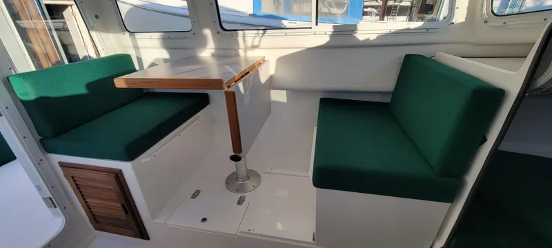 Slide: The Image of 2025 C-Dory 22' Cruiser interior with green seating and wooden table. - 6