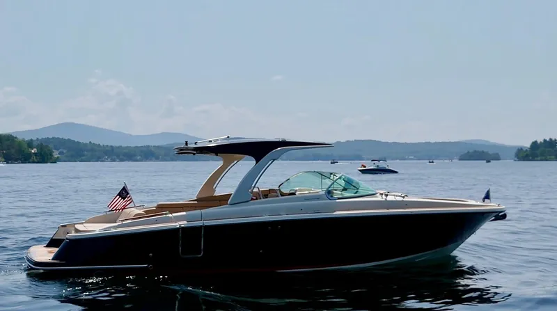 Slide: The Image of 2021 Chris-Craft Launch 35 GT boat on a serene lake with distant hills. - 1