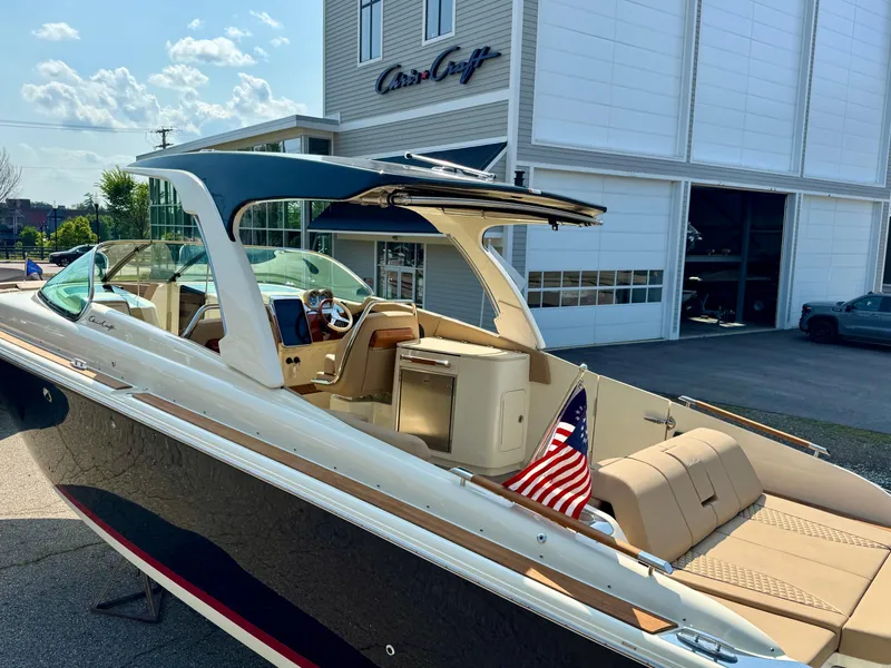 Slide: The Image of 2021 Chris-Craft Launch 35 GT boat with American flag, parked outside showroom. - 26