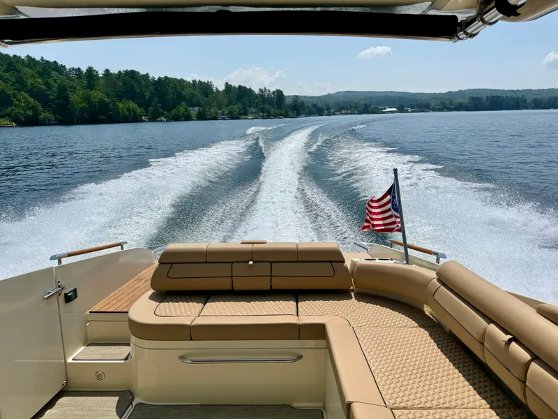 Slide: The Image of 2021 Chris-Craft Launch 35 GT cruising on a lake, American flag waving, scenic forested shoreline. - 5