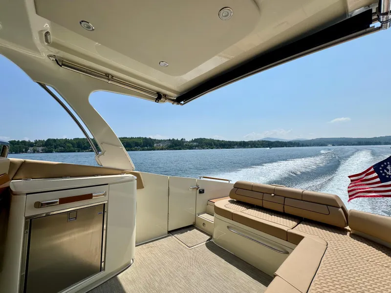 Slide: The Image of 2021 Chris-Craft Launch 35 GT cruising on a sunny lake, featuring luxurious seating and American flag. - 6