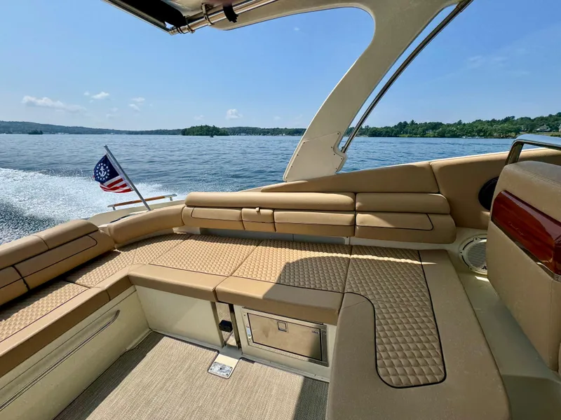 Slide: The Image of 2021 Chris-Craft Launch 35 GT interior with tan seating, cruising on a lake under clear skies. - 7