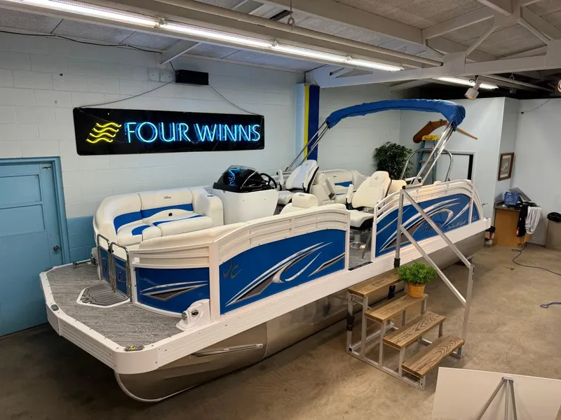 Slide: The Image of 2024 JC Neptoon 23 TT DSL pontoon boat displayed indoors with blue accents. - 17