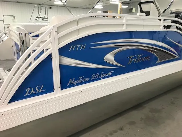 Slide: The Image of 2024 JC Neptoon 23 TT DSL pontoon boat with blue and white design in a showroom. - 3