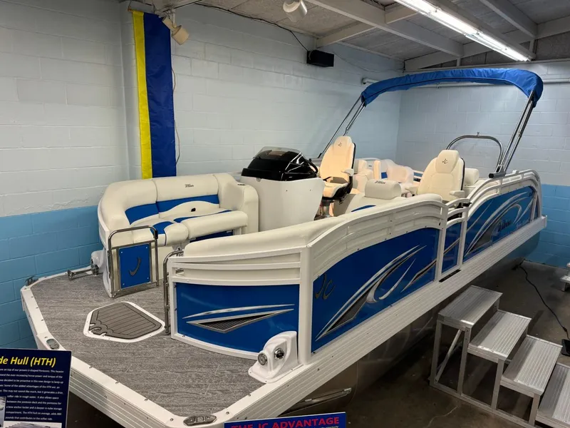 Slide: The Image of 2024 JC Neptoon 23 TT DSL pontoon boat with blue accents in showroom. - 8