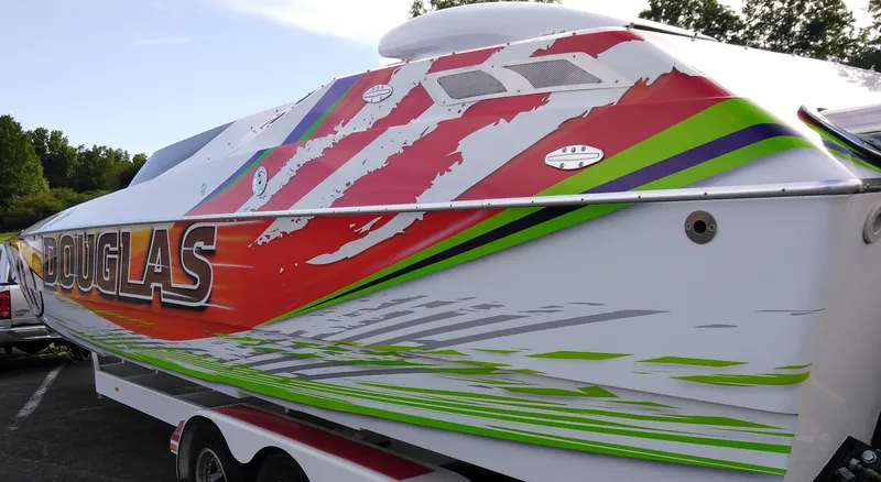Slide: The Image of 1999 Skater 32 boat with vibrant red, green, and white graphics on a trailer. - 10
