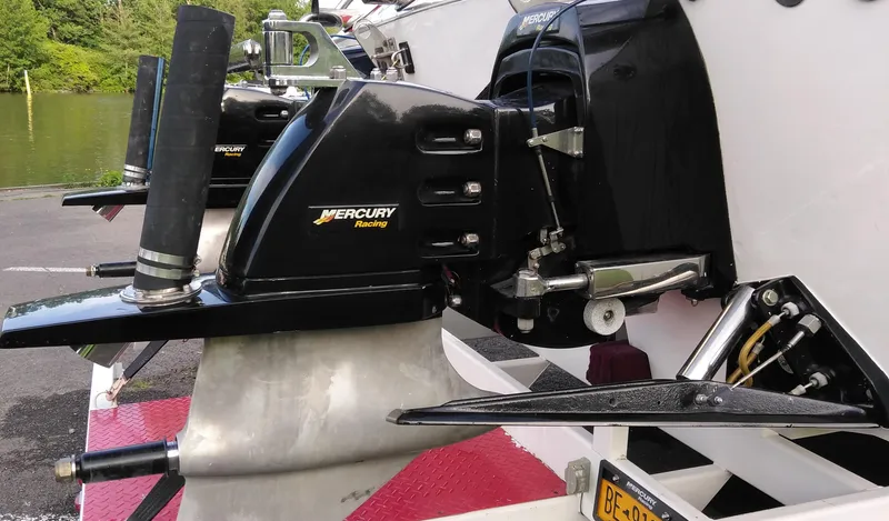 Slide: The Image of 1999 Skater 32 boat with Mercury Racing engines, docked near a lake. - 12