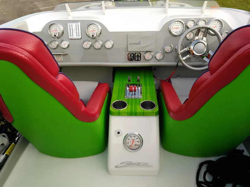 Slide: The Image of 1999 Skater 32 boat cockpit with red and green seats, steering wheel, and control panel. - 15