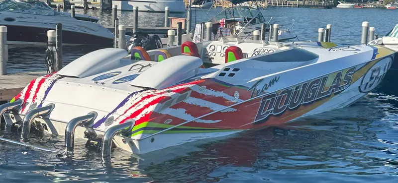 Slide: The Image of 1999 Skater 32 powerboat with vibrant graphics docked at a marina. - 23