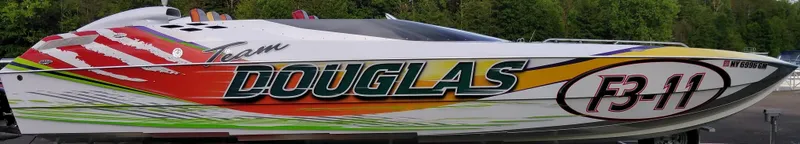 Slide: The Image of 1999 Skater 32 powerboat with vibrant "Team Douglas" graphics, parked outdoors. - 3