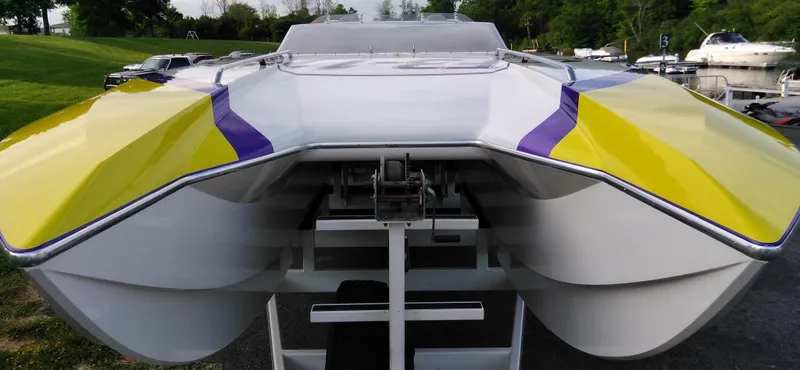 Slide: The Image of 1999 Skater 32 catamaran with yellow and purple accents, docked outdoors. - 6