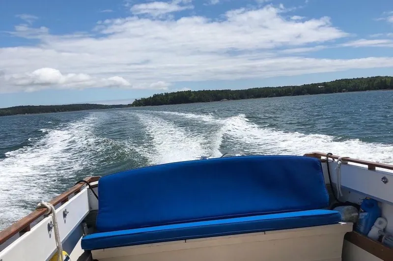 Slide: The Image of 1975 Lyman 26 Cruisette on open water, blue seating, scenic view. - 14
