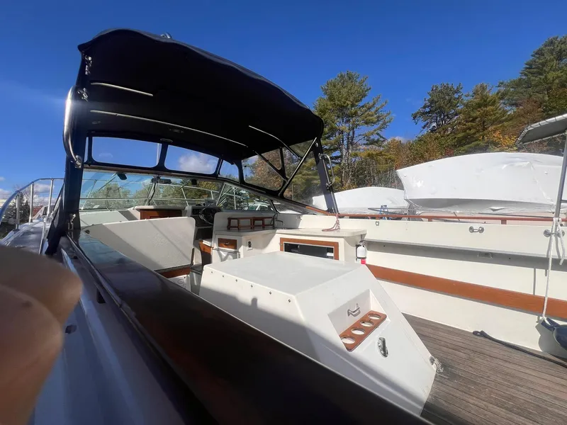 Slide: The Image of 1975 Lyman 26 Cruisette boat with canopy, docked under clear blue sky. - 15