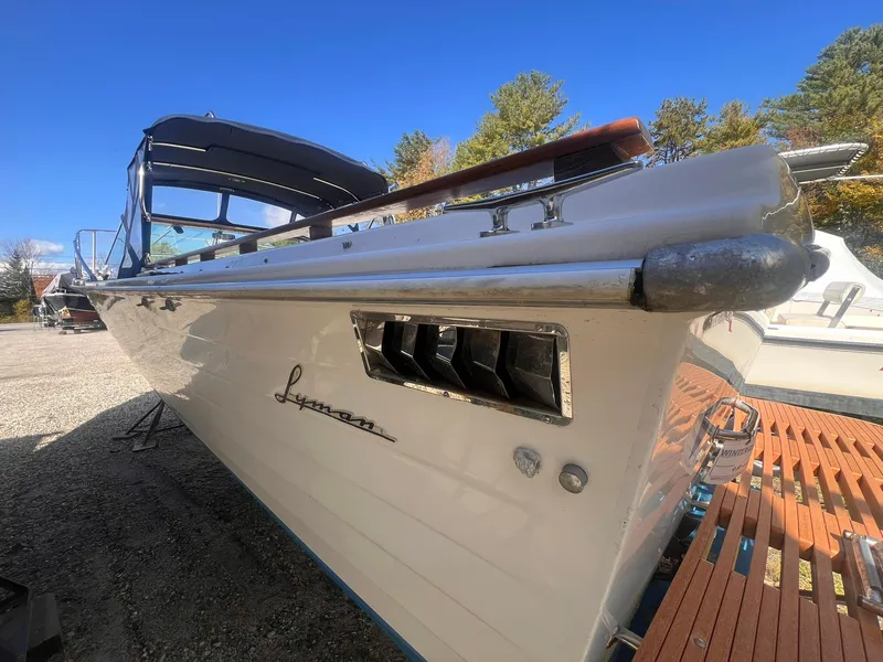 Slide: The Image of 1975 Lyman 26 Cruisette boat with sleek design, docked outdoors under clear blue sky. - 19