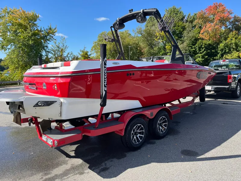 Slide: The Image of Red 2023 Axis A225 boat on trailer, parked outdoors with trees in background. - 10