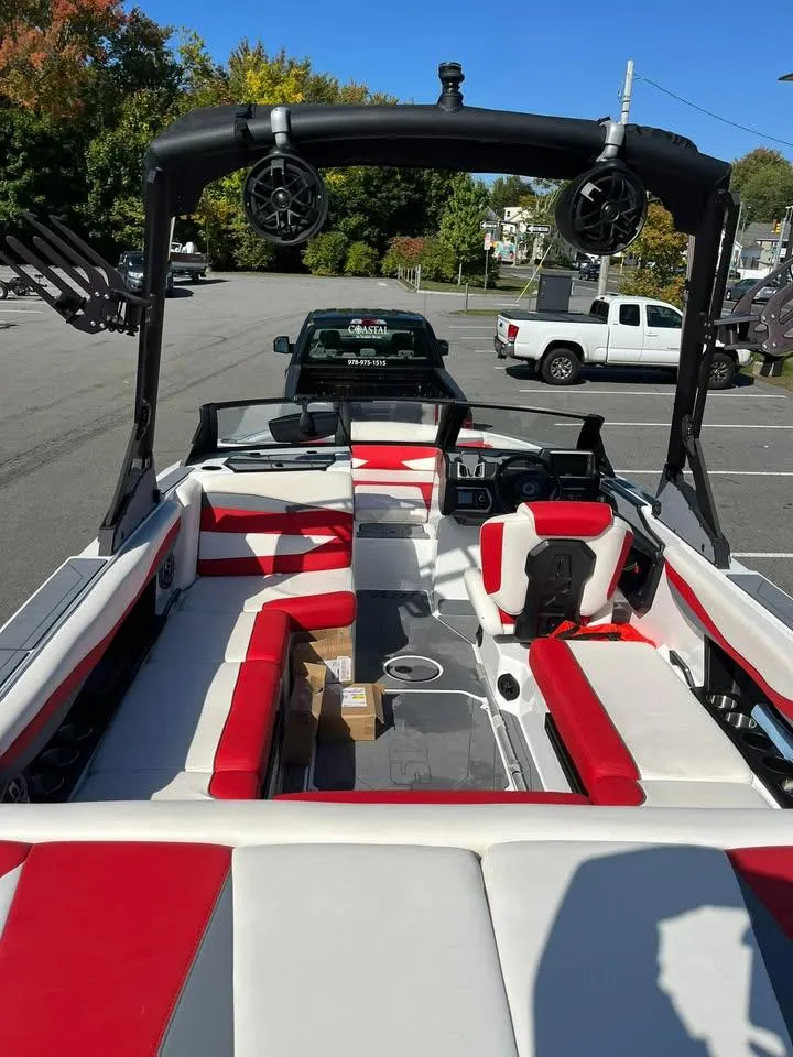 Slide: The Image of 2023 Axis A225 boat with red and white seating, parked in a lot. - 4