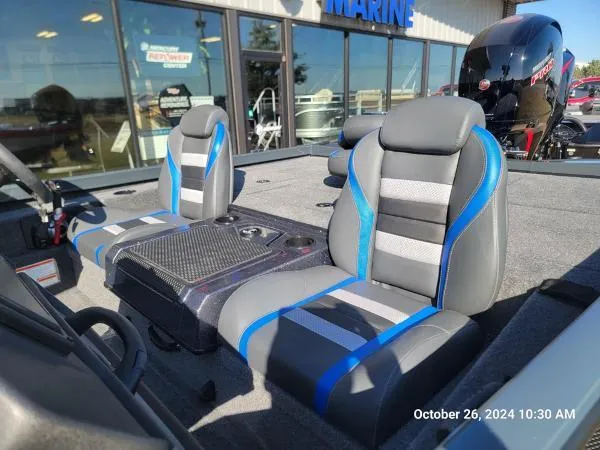 Slide: The Image of 2025 Ranger RT198P boat interior with gray and blue seats, outside a marine shop. - 2