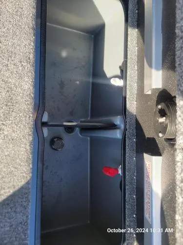 Slide: The Image of 2025 Ranger RT198P boat storage compartment, open and empty, with visible latch and carpeted edges. - 3
