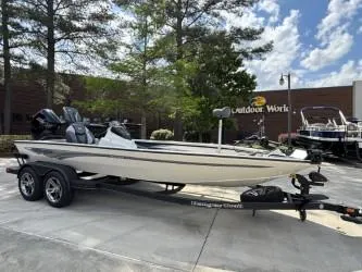 Slide: The Image of 2025 Ranger ALPHA 208 boat on trailer, parked outdoors near trees and building. - 1